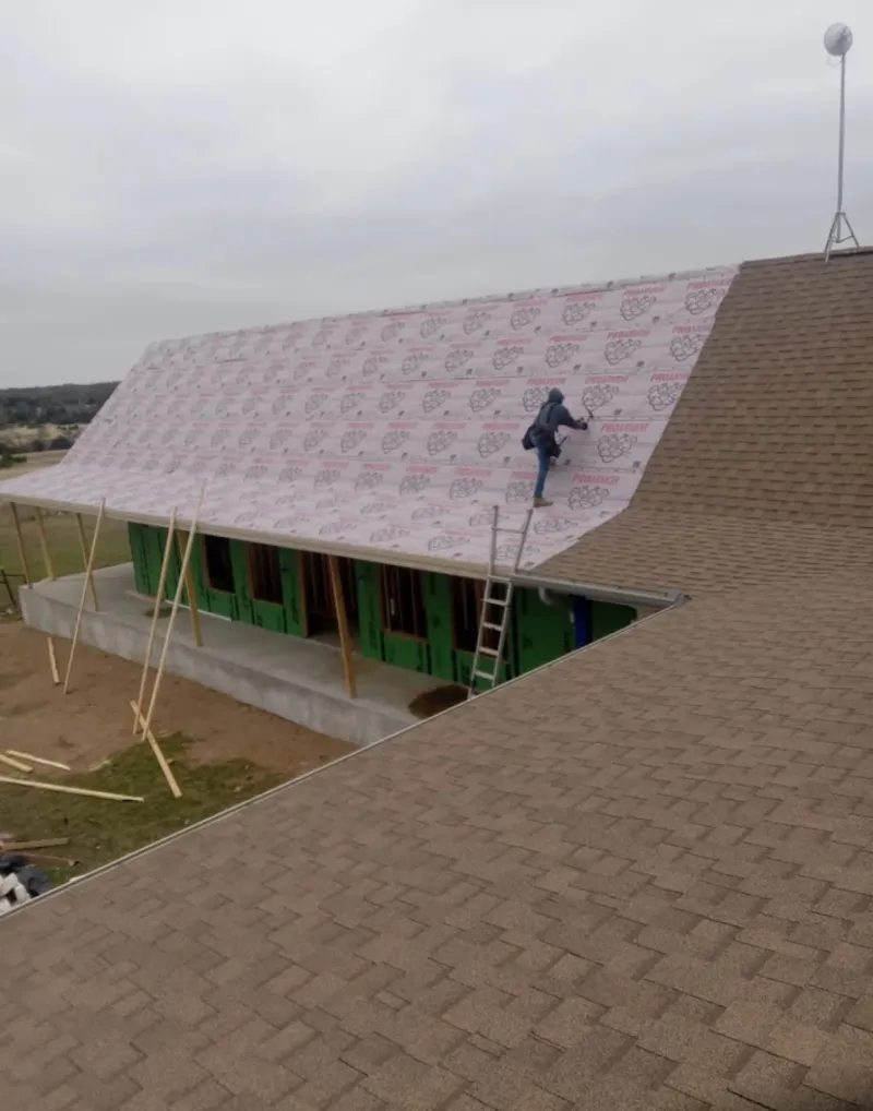 Worker preparing underlayment for a metal roof installation in Lexington